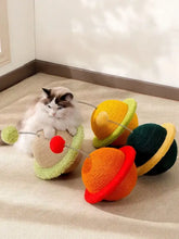 Flauschige weiße und braune Katze auf einem planetenförmigen interaktiven Katzenspielzeug