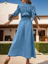 A light blue denim dress with puffed half sleeves tied at the cuffs and a slightly stretchy gathered waist