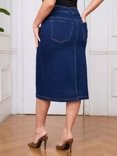 Back view of a plus size dark blue denim skirt with classic pockets and visible stitching made from slightly stretchy fabric