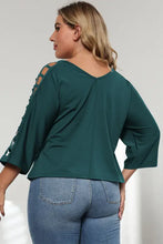 Plus size dark teal V-neck top with lattice sleeve cutout and blue jeans