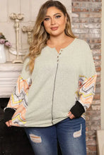 Plus size exposed seam print long sleeve T-shirt in light green knit with patterned sleeves and distressed jeans