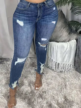 Plus size slim fit distressed jeans in blue denim with ripped knees and frayed cuffs for casual wear