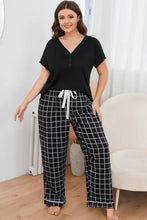 Plus size v-neck top and plaid pants lounge set featuring black and white checkered pajama pants with white drawstring waistband and long sleeve length top
