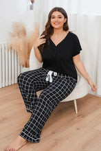 Plus size v-neck top and plaid pants lounge set featuring black and white checkered pajama pants with white drawstring waistband and long sleeve length top