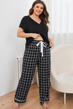 Plus size v-neck top and plaid pants lounge set featuring black and white checkered pajama pants with white drawstring waistband and long sleeve length top