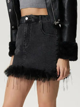 Black denim mini skirt with fuzzy fringe hem paired with jacket featuring faux fur trim on cuffs