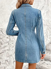 A fitted medium-wash pocketed button up long sleeve denim dress with collar and long sleeve denim design