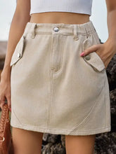 Beige mini denim skirt with buttoned flap pockets and a relaxed high-waisted fit in soft denim fabric