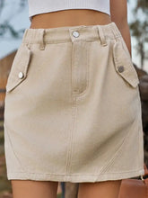 Beige mini denim skirt with buttoned flap pockets and fitted waistband in a pocketed buttoned mini denim skirt