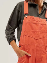Person in pocketed wide strap denim overalls with front pocket