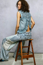 Back view of blue denim patchwork pants with floral accents paired with pol button closure cotton blouse with ruffled detail