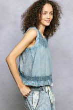 Light blue cotton blouse with pol button closure on back, ruffled sleeveless design, and embroidered neckline trim detail
