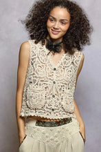 Cream-colored cropped crochet vest with scalloped edge featuring intricate lace patterns and dark pol button closures