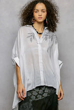 Lightweight sheer white button-up blouse with delicate black embroidered floral design and high low hem shirt style