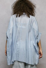Light blue pol button loose-fitting blouse with slightly sheer fabric and high low hem for a relaxed look