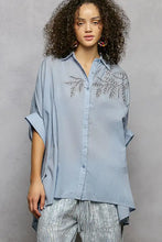 Light blue pol button down shirt with delicate silver leaf embroidery and stylish high low hem design