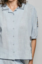 Light blue lightweight woven pol button down embroidered floral shirt with dark embellished collar and cuffs