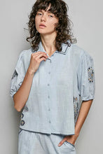 Light blue lightweight woven linen blouse with embroidered floral design and beaded trim on collar cuffs and hem