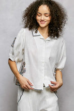 White linen embroidered floral short sleeve blouse with black floral details and dotted trim on collar sleeves and hem