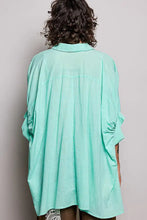 A loose-fitting mint green cotton blouse with rolled-up sleeves and a classic collar featuring half dolman sleeves