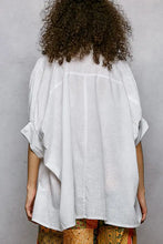 White linen blouse with relaxed fit and loose flowing sleeves featuring a half dolman sleeve design