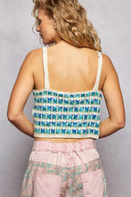 A teal and cream crocheted cropped cami with scalloped edge and textured pattern made from lightweight yarn