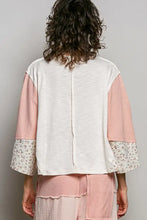 A white and blush pink textured slub knit patchwork top with round neck and floral-patterned cuffs