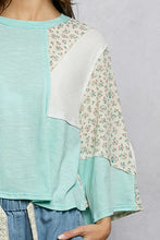 A mint green and white textured slub knit patchwork top with floral patterned sleeves and a round neck design