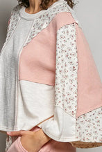 A gray pink and white textured slub knit round neck sweater with floral patchwork sleeves in a soft patchwork style