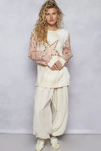 Cream-colored star patch thermal top with sheer floral sleeves and exposed shoulder seam detail