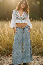 Wide-leg denim pants with patchwork design and decorative tassels paired with pol floral embroidered cropped blouse