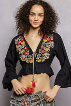Black floral embroidered cropped blouse with red and gold patterns, bell sleeves, and a ruffled hem
