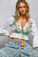 White cropped blouse with colorful floral embroidery and ruffled hem in pol floral embroidered style