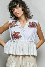 White sleeveless pol floral patch top with colorful floral embroidery, raw edge detail, and peplum hem