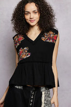 Black sleeveless top with vibrant pol floral patch embroidery and raw edge detail featuring a peplum hem