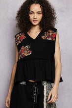 Black sleeveless top with vibrant red orange and gold floral patch embroidery and raw edge detail on shoulders and chest
