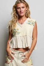 Cream-colored floral patch ruffled sleeveless top with raw edge detail and embroidered ruffled hem