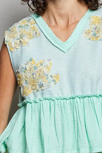 A light mint green pol floral patch ruffled sleeveless top with raw edge detail and yellow blue embroidery