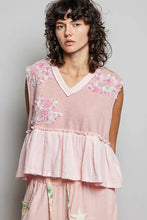 A soft pink sleeveless top with floral patch ruffled embroidery on shoulders and a tiered ruffled hem