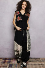 Black sleeveless top with vibrant pol floral patch embroidery and raw edge detail on shoulders and chest