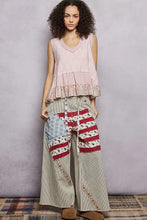 Patchwork wide-leg pants with striped fabric and patriotic print patches styled with a pol floral textured tank