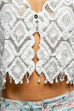 White crocheted lace crop top with intricate floral patterns, central button closure, and scalloped edge fringe trim