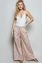 A pair of wide-leg high-waisted pants with soft pink and green floral vertical stripes paired with pol lace neck ribbed cami