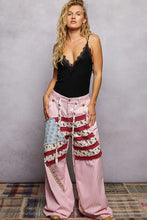 Pink corduroy wide-leg pants with patchwork red white and blue star panels styled with pol lace neck ribbed cami
