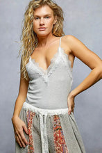 A light gray pol lace ribbed cami with delicate spaghetti straps and lace detail on a soft textured fabric