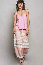 A pink layered maxi skirt with lace trim and crisscross lacing paired with a textured knit cami