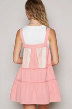 Back view of pink denim overall dress with lace patchwork panels and adjustable straps in tiered design