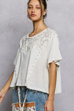 White loose-fitting short sleeve shirt with round neck featuring lace and pearl stud embellishments