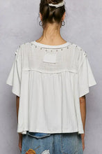 White sheer loose-fitting short sleeve shirt with round neck and silver pearl stud embellishments on shoulders
