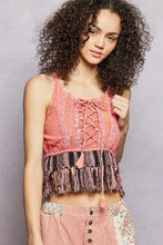 A coral-colored lace-trimmed crop top with corset-style lacing and a fringe hem tank detail
